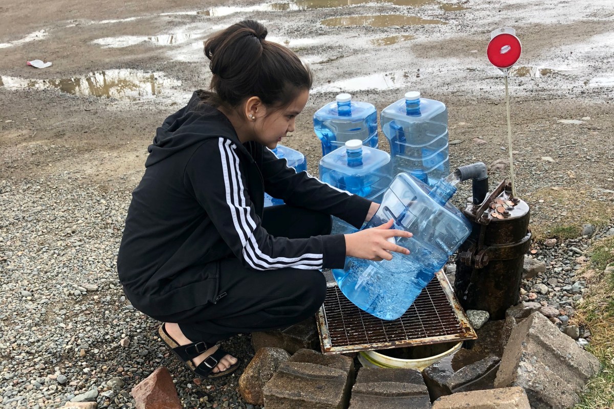 Young woman filling water jugs from clean drinking water well