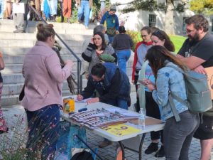 Group of people around a table with forms to sign up for canvassing for Question 6