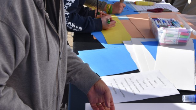 Participants made signs to hold during the rally and march. Photo: Anne Henshaw person wearing grey jackets creating a sign with text vote for truth yes on 6