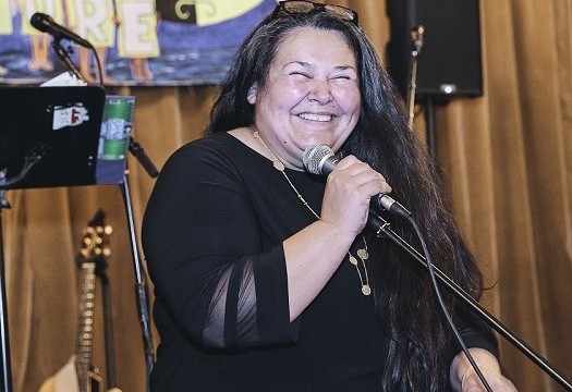 Chief Clarissa Sabattis of the Houlton Band of Maliseet Indians. Chief Clarissa Sabattis of the Houlton Band of Maliseet Indians stands at a microphone smiling wearing black sweater
